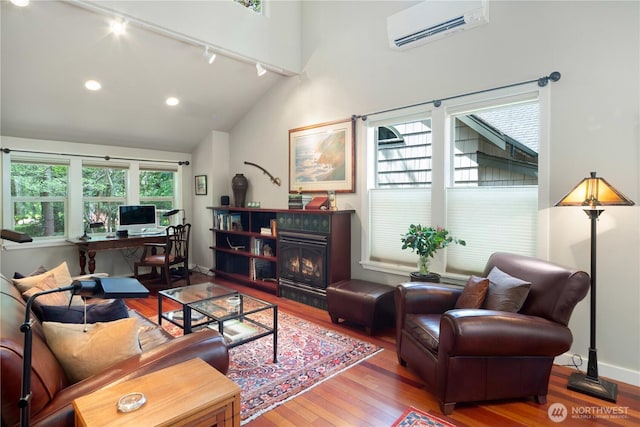 living area featuring track lighting, a wall mounted AC, wood finished floors, a desk, and lofted ceiling