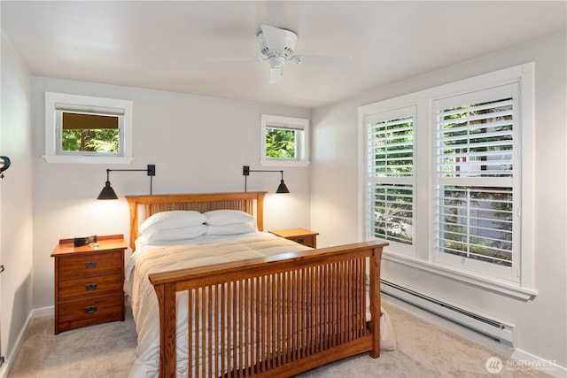 bedroom featuring baseboard heating, light colored carpet, baseboards, and a ceiling fan