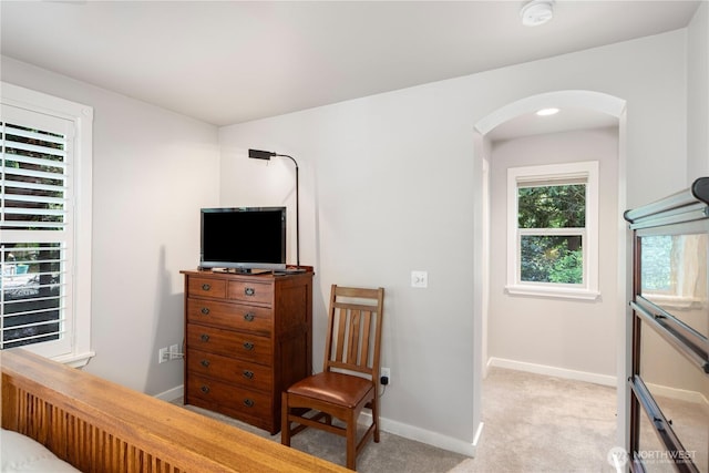 bedroom with arched walkways, baseboards, and light colored carpet