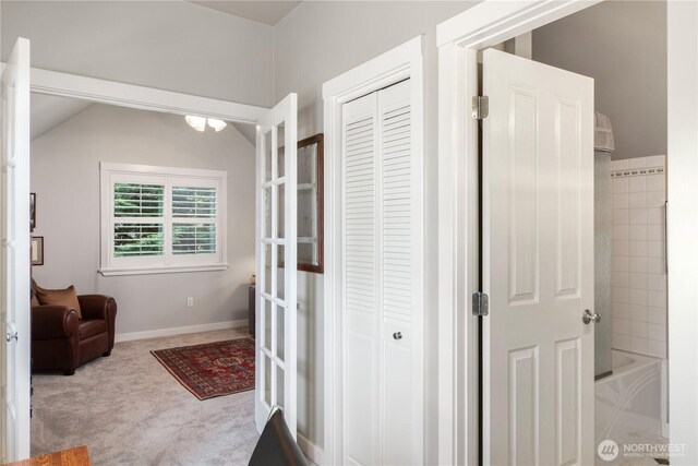hall featuring carpet flooring, vaulted ceiling, and baseboards