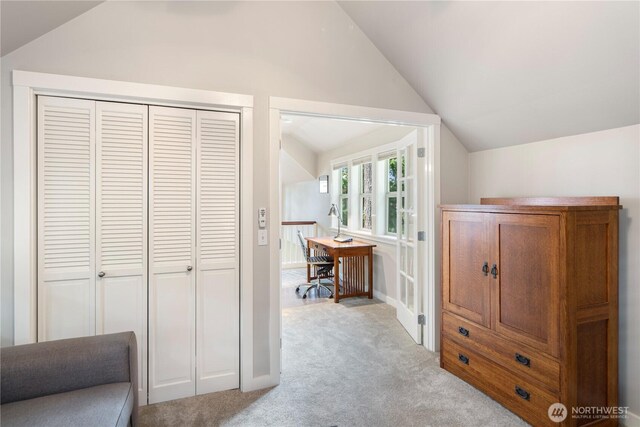 corridor featuring vaulted ceiling, light colored carpet, and a desk