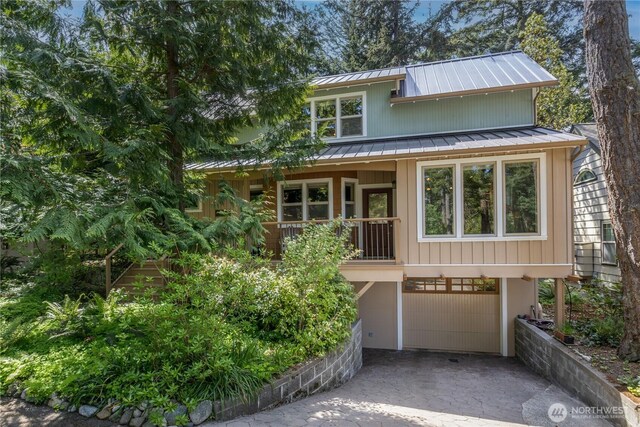 view of front facade featuring driveway, a garage, a standing seam roof, and metal roof