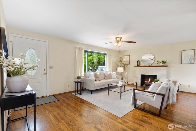 living area with a ceiling fan, a fireplace, light wood-style floors, and baseboards