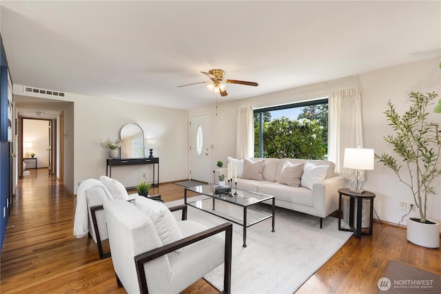 living area with a ceiling fan, wood finished floors, and baseboards