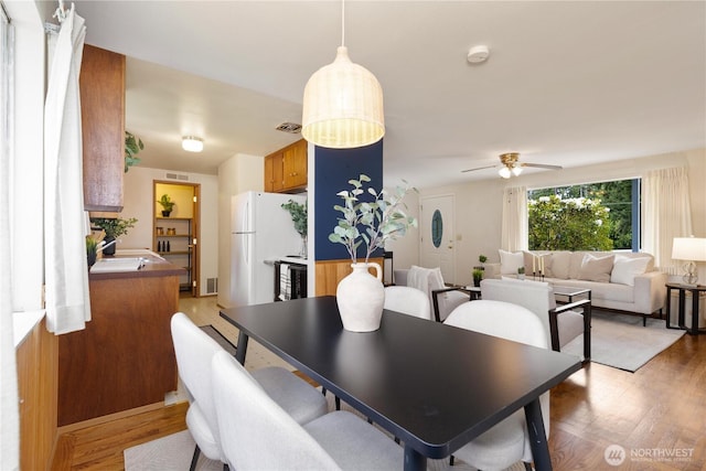 dining room with light wood-type flooring and a ceiling fan
