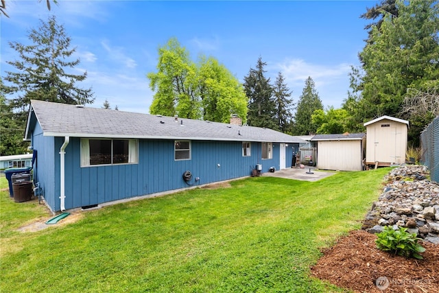 back of property with a storage shed, a patio area, an outdoor structure, a chimney, and a lawn