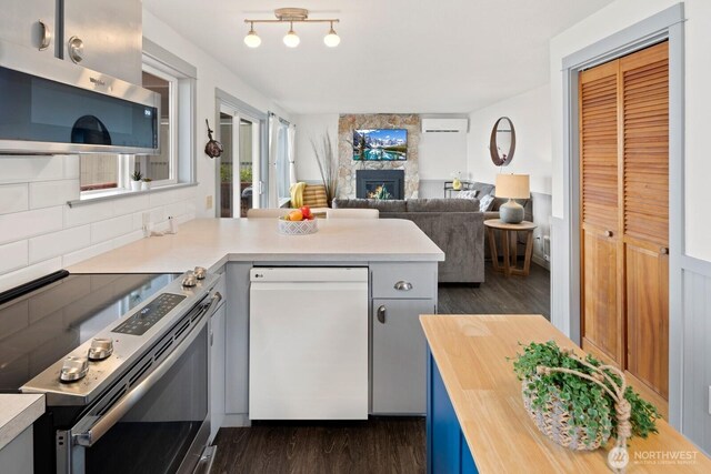 2967 Saratoga Rd, Langley, WA 98260 - kitchen featuring appliances with stainless steel finishes, butcher block counters, dark wood-type flooring, and a stone fireplace