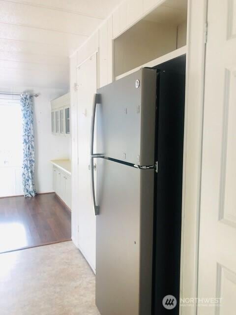 kitchen with freestanding refrigerator, white cabinetry, and wood finished floors