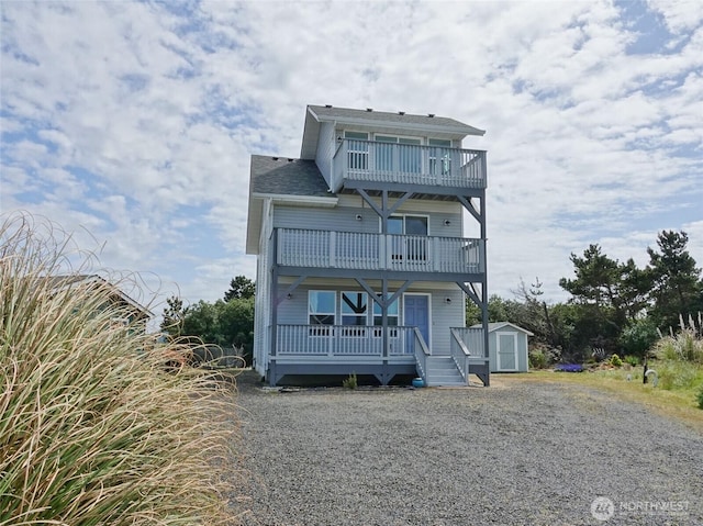view of front of property featuring a balcony, a shed, an outdoor structure, a porch, and driveway