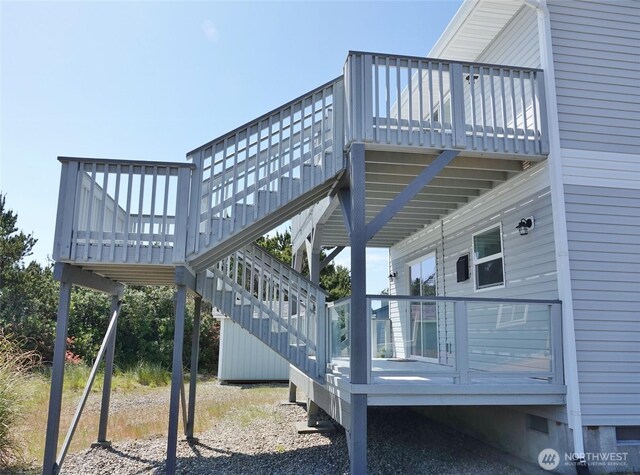 view of side of home featuring stairway, a wooden deck, and crawl space
