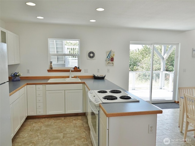 kitchen featuring a sink, white appliances, a peninsula, white cabinetry, and recessed lighting