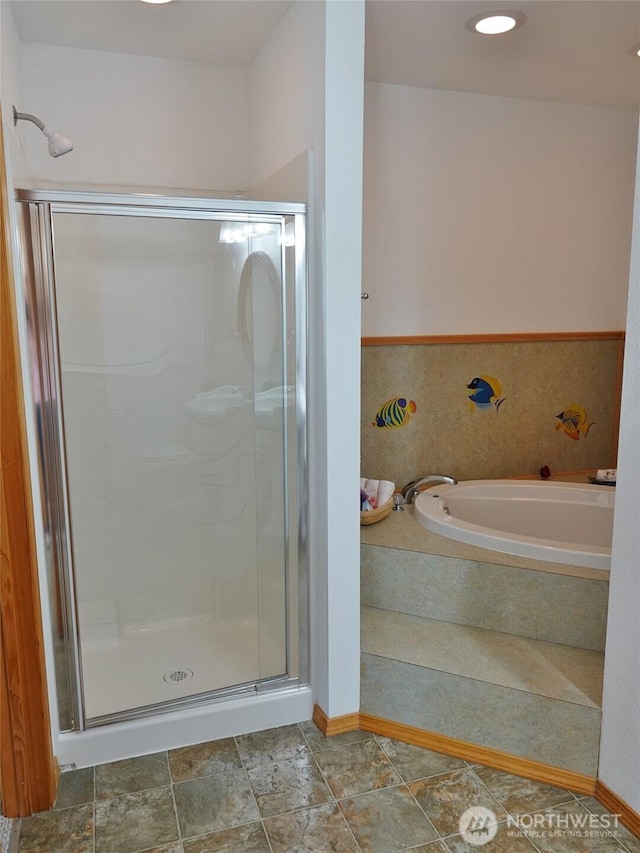 full bathroom with a shower stall, a garden tub, and baseboards