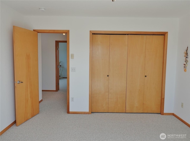 unfurnished bedroom featuring carpet, baseboards, and a closet