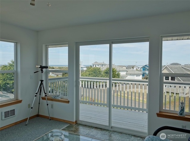 doorway to outside with healthy amount of natural light, baseboards, carpet, and a residential view