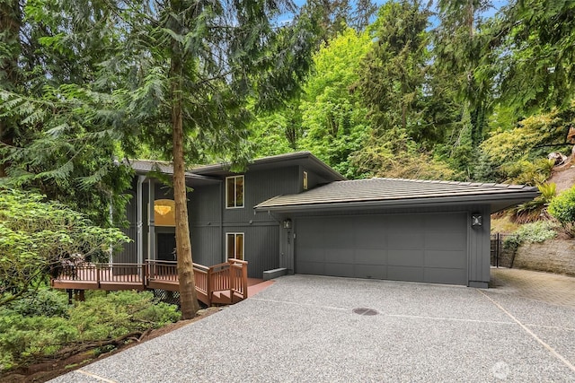 view of front facade featuring an attached garage, concrete driveway, a deck, and a tiled roof