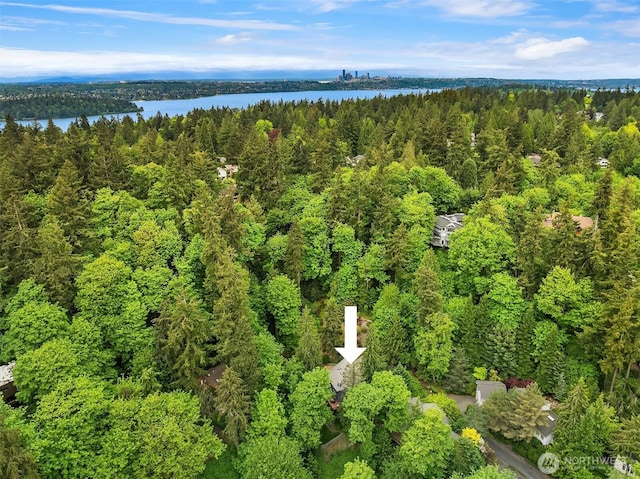 aerial view of property and surrounding area with a forest and a nearby body of water