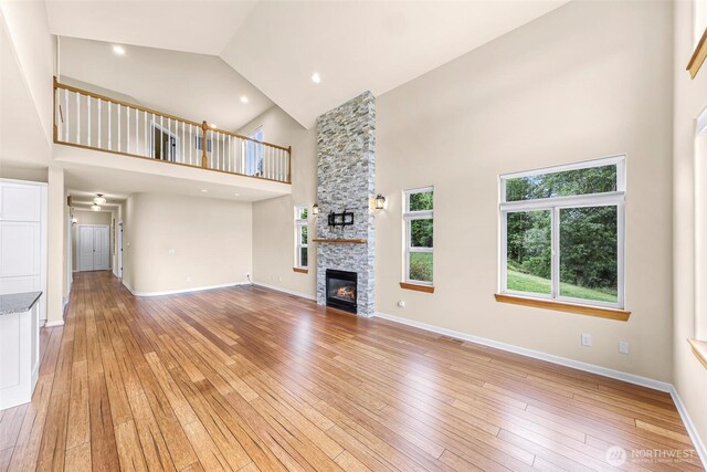 549 E Maberry Dr, Lynden, WA 98264 - unfurnished living room with high vaulted ceiling, a stone fireplace, light wood-style flooring, and baseboards