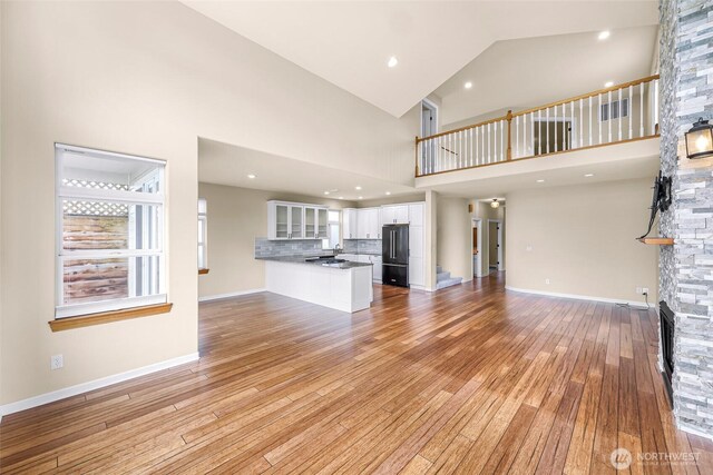 549 E Maberry Dr, Lynden, WA 98264 - unfurnished living room with a stone fireplace, light wood finished floors, high vaulted ceiling, and baseboards