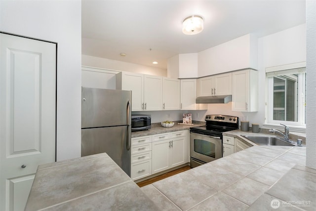 kitchen with stainless steel appliances, a sink, under cabinet range hood, and light countertops