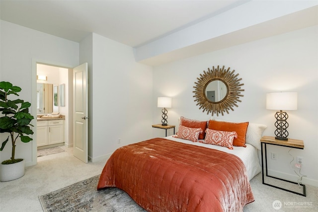 bedroom featuring light colored carpet, ensuite bathroom, and baseboards