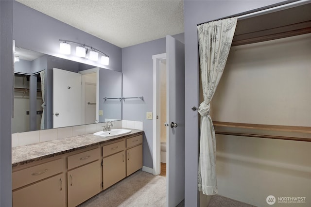 bathroom featuring toilet, vanity, a textured ceiling, and baseboards