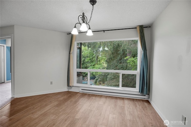 unfurnished dining area with a baseboard heating unit, wood finished floors, a textured ceiling, a chandelier, and baseboards