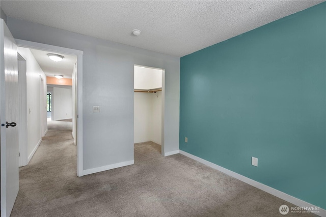 unfurnished bedroom with carpet, a closet, baseboards, and a textured ceiling