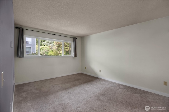 carpeted empty room with a textured ceiling and baseboards