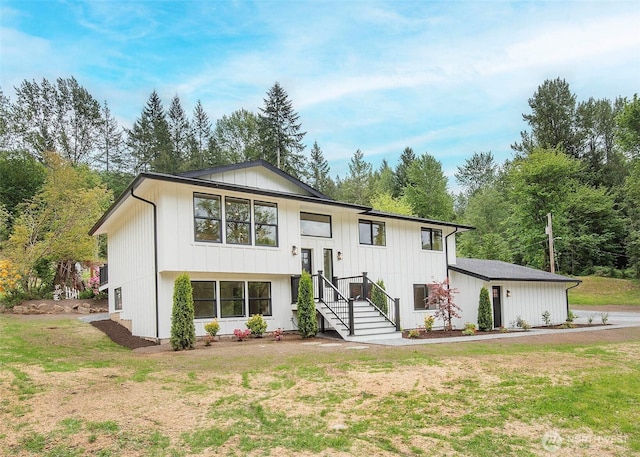 raised ranch featuring a front lawn and board and batten siding