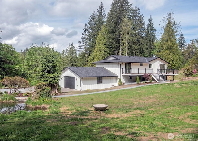 view of front of home featuring a front lawn, a deck, stairs, and an attached garage