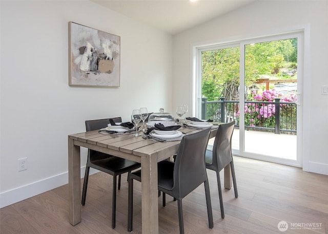 dining room featuring lofted ceiling, baseboards, and light wood-style flooring