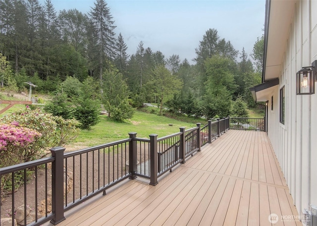 wooden terrace with a lawn and a wooded view