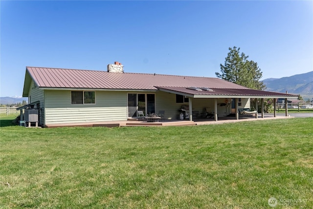 back of house with a mountain view, a patio area, a lawn, and a chimney