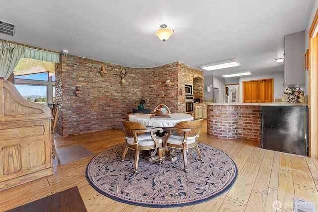 dining area featuring brick wall and hardwood / wood-style floors