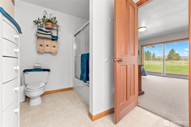 bathroom with baseboards, bath / shower combo with glass door, and toilet