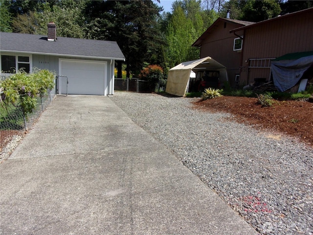 view of home's exterior with concrete driveway, fence, a chimney, and an attached garage