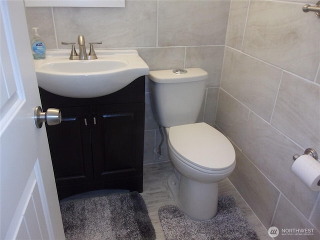 bathroom featuring tile walls, vanity, and toilet