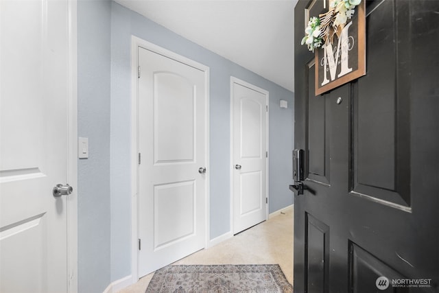 entrance foyer featuring baseboards and light colored carpet