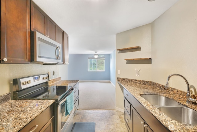 kitchen featuring appliances with stainless steel finishes, a sink, baseboards, and light stone countertops