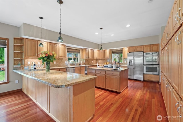 35449 34th Ave S, Auburn, WA 98001 - kitchen with appliances with stainless steel finishes, tasteful backsplash, wood finished floors, a peninsula, and a kitchen island with sink