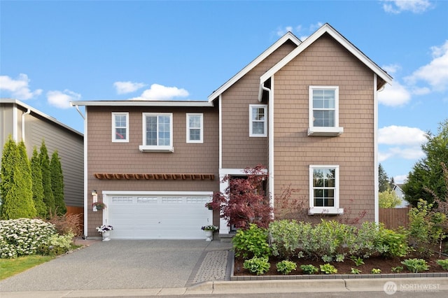 view of front facade with concrete driveway, a garage, and fence