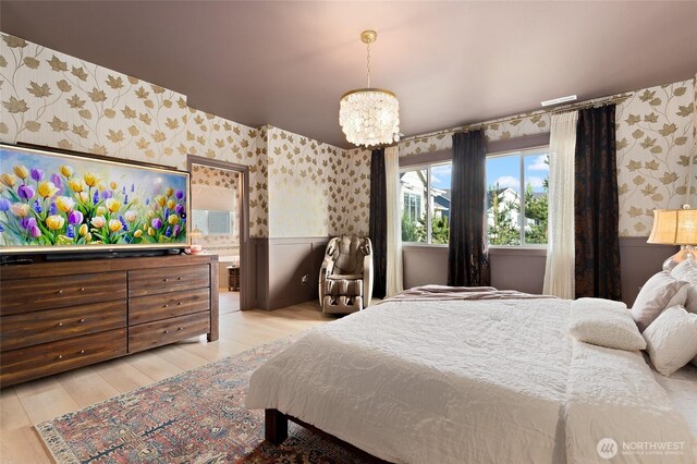 bedroom featuring wallpapered walls, wainscoting, light wood finished floors, and a chandelier