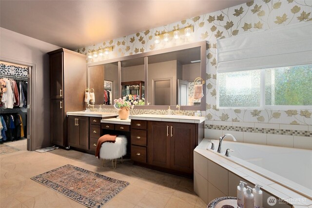 full bath featuring vanity, wallpapered walls, a bath, a walk in closet, and tile patterned flooring