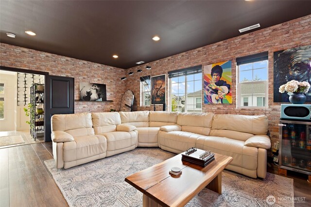 living area with brick wall, wood finished floors, and recessed lighting