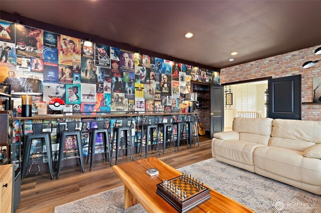 living area with wood finished floors, brick wall, and recessed lighting