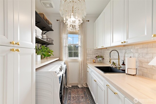 laundry area featuring cabinet space, washer and clothes dryer, and a chandelier