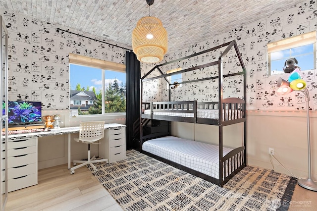bedroom with wallpapered walls and light wood-style flooring