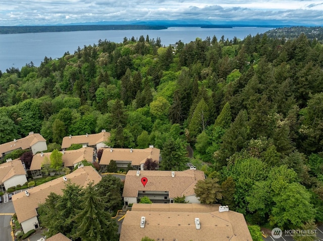 aerial view of property and surrounding area featuring a forest, a large body of water, and nearby suburban area