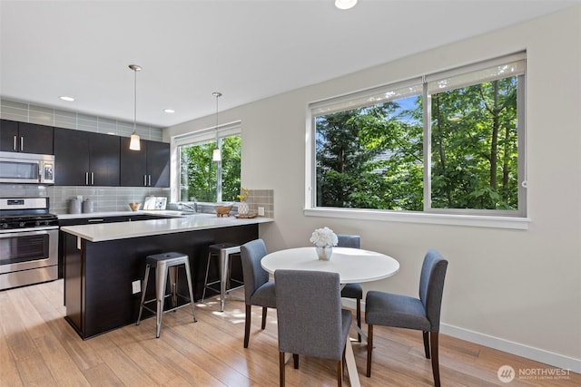 dining room with light wood-type flooring, baseboards, and recessed lighting
