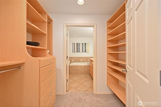 walk in closet with light colored carpet and light tile patterned floors